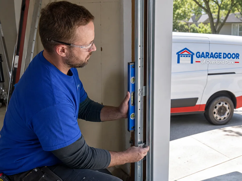 Contractor leveling vertical garage door tracks and checking jamb fasteners during replacement
