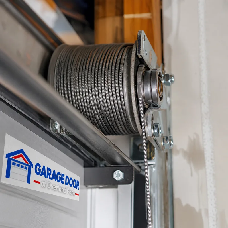 Close-up of a garage door lift cable seated in the cable drum grooves beside the end bearing plate