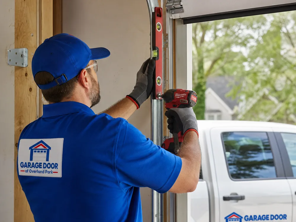 Contractor checking vertical garage door track alignment with a level and tightening track brackets