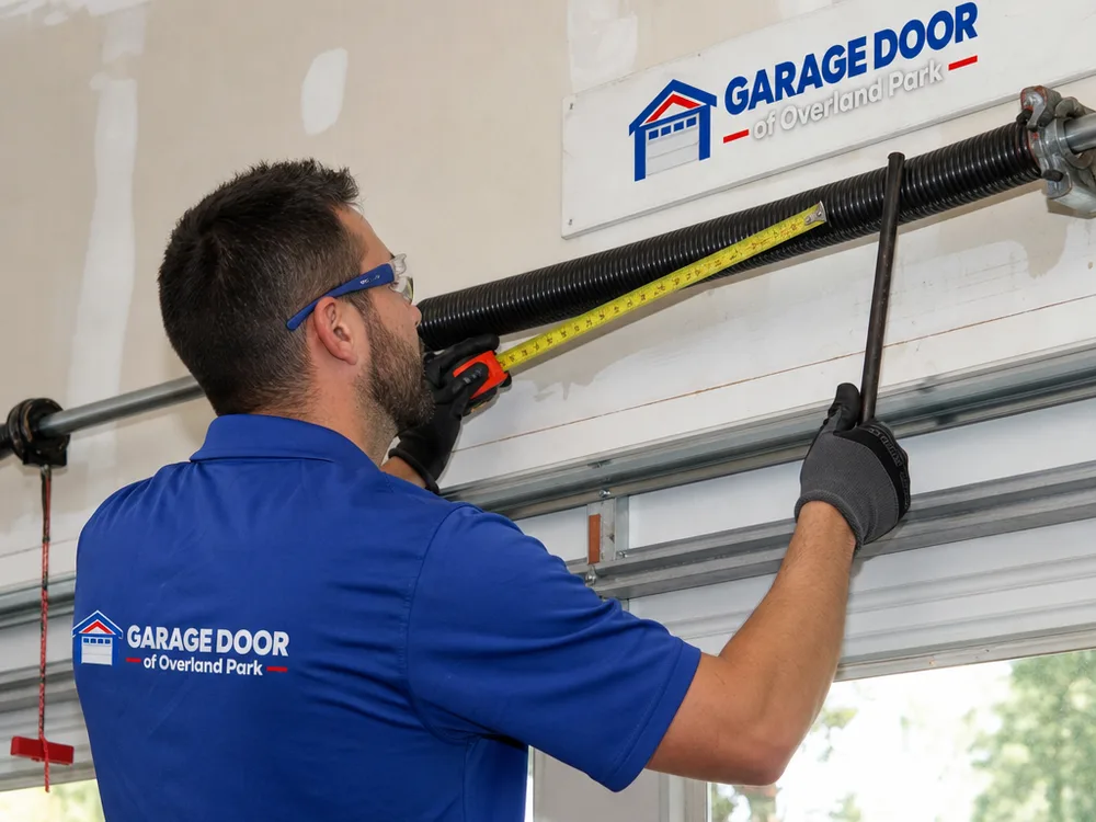 Contractor measuring a garage door torsion spring assembly with winding bars and safety glasses visible